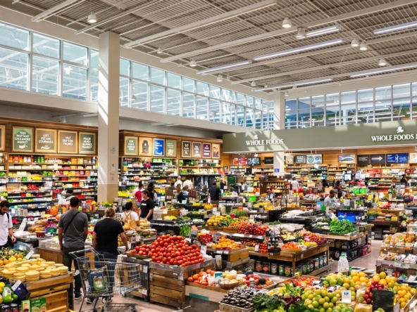 Colorful fresh produce, prepared foods, and shoppers inside Whole Foods.