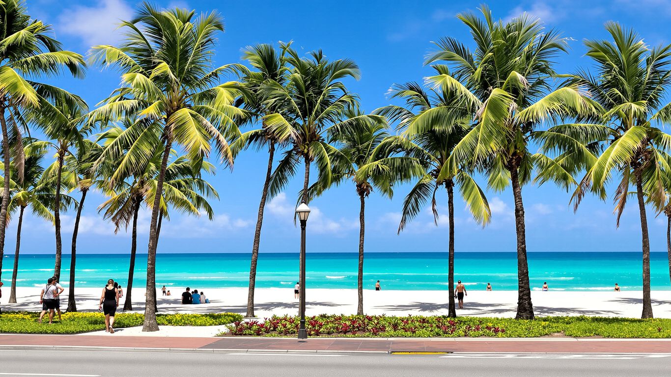 Miami Beach Boardwalk with palm trees, ocean, and sandy beach.